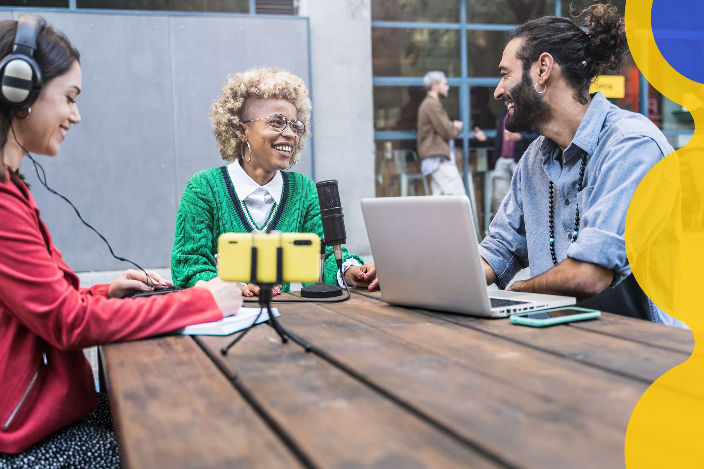 A group of young people sit around a table at an outside cafe having a lively conversation