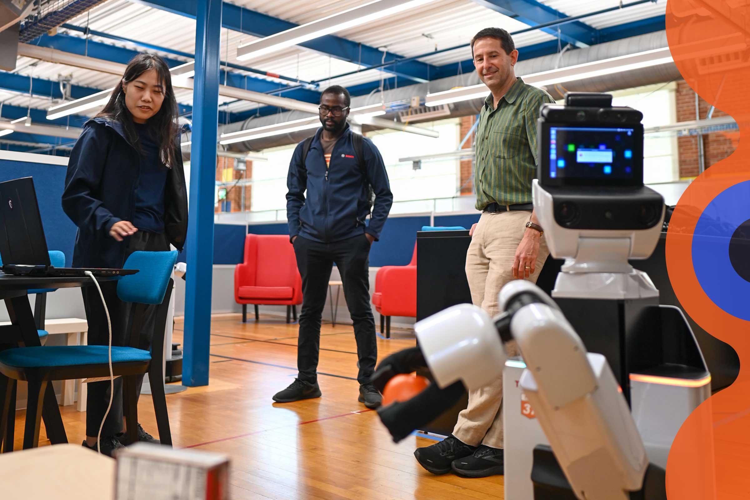 Group of researchers looking at a robot about to pick up a box